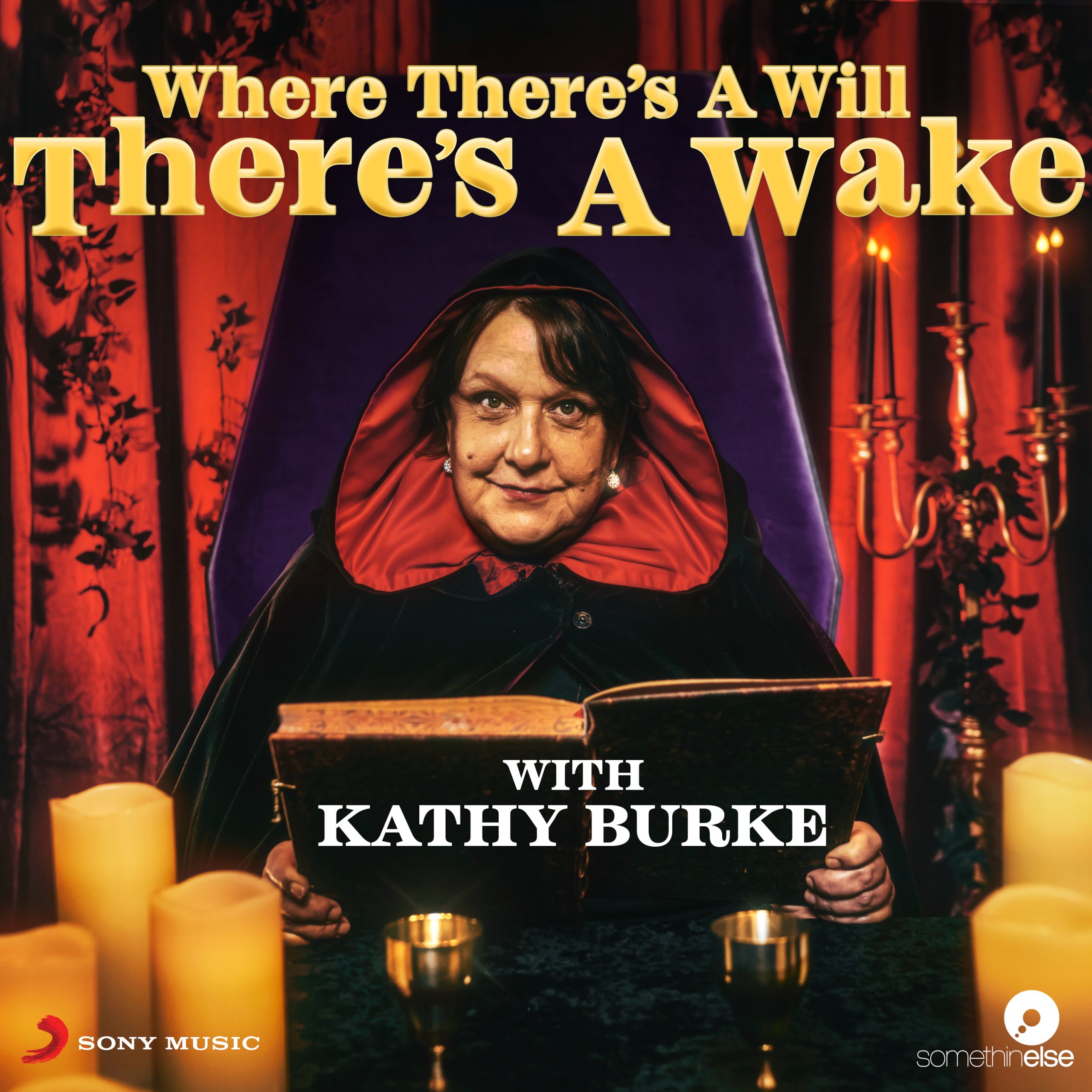 Kathy Burke in a coffin chair, reading from a book with candles around her