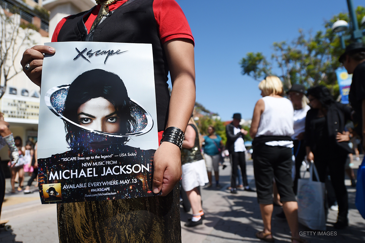 Dancer holds poster for Xscape after Michael Jackson tribute flash mob dance on 3rd Street Promenade in Santa Monica, CA, June 22, 2014